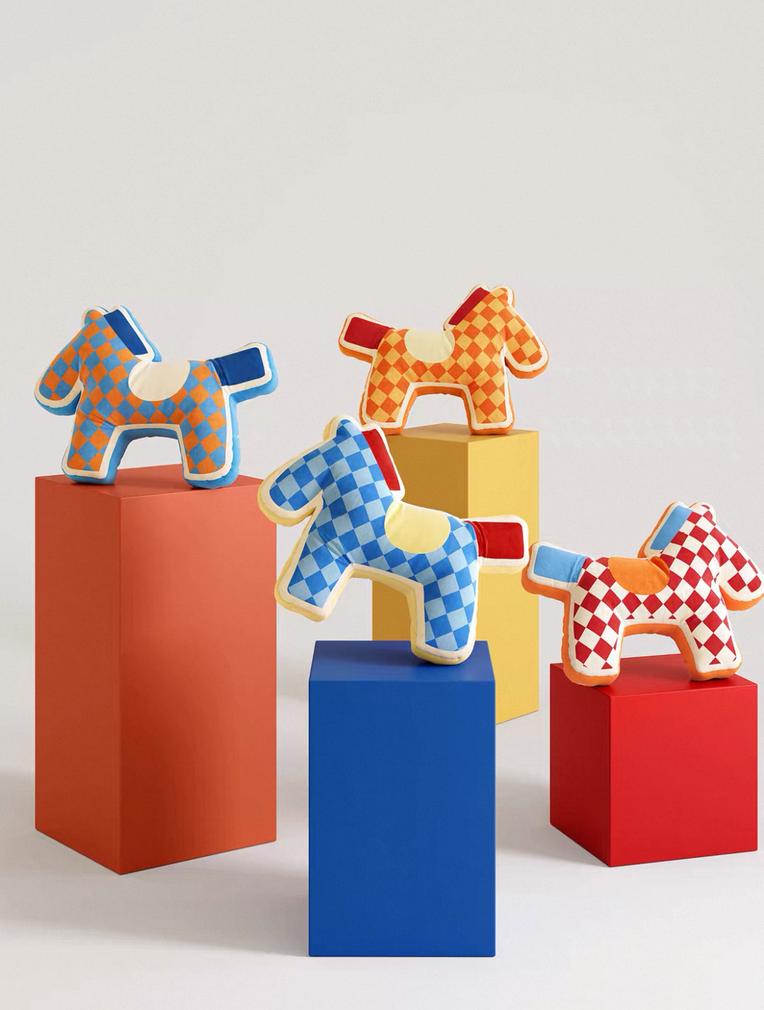 A set of colorful wooden toy horses with checkered patterns displayed on matching colored pedestals against a light gray background.