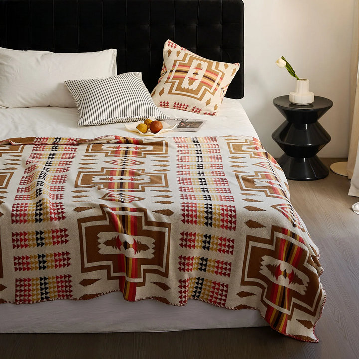 Bed with patterned blanket and pillows in a bedroom setting