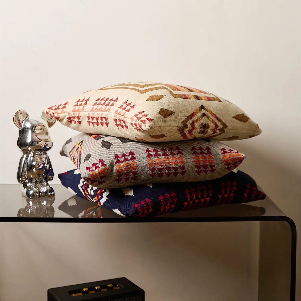 Three stacked Ethnic Knitted pillows in cream, gray and navy with colorful geometric patterns. 