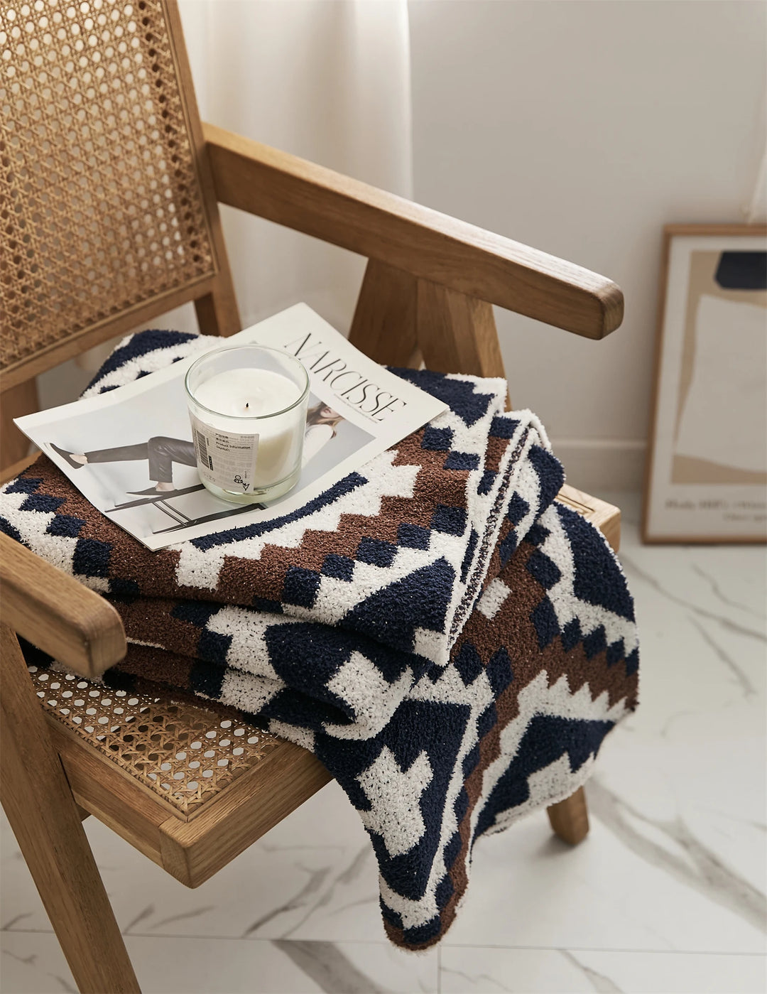 Geometric quilt blanket draped over a chair, in cream, brown, and navy