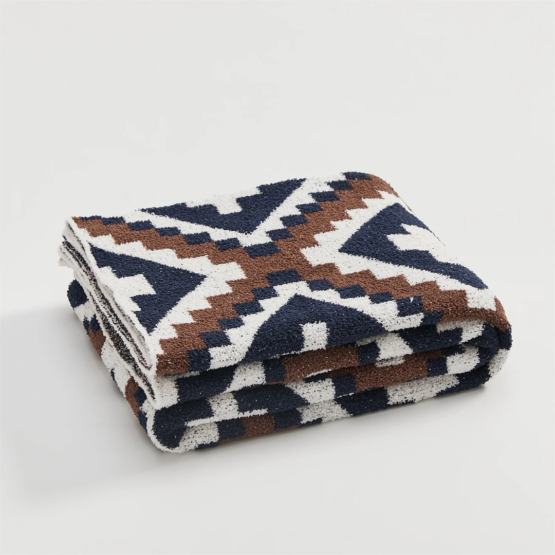 Folded geometric quilt blanket with cream, brown, and navy motifs