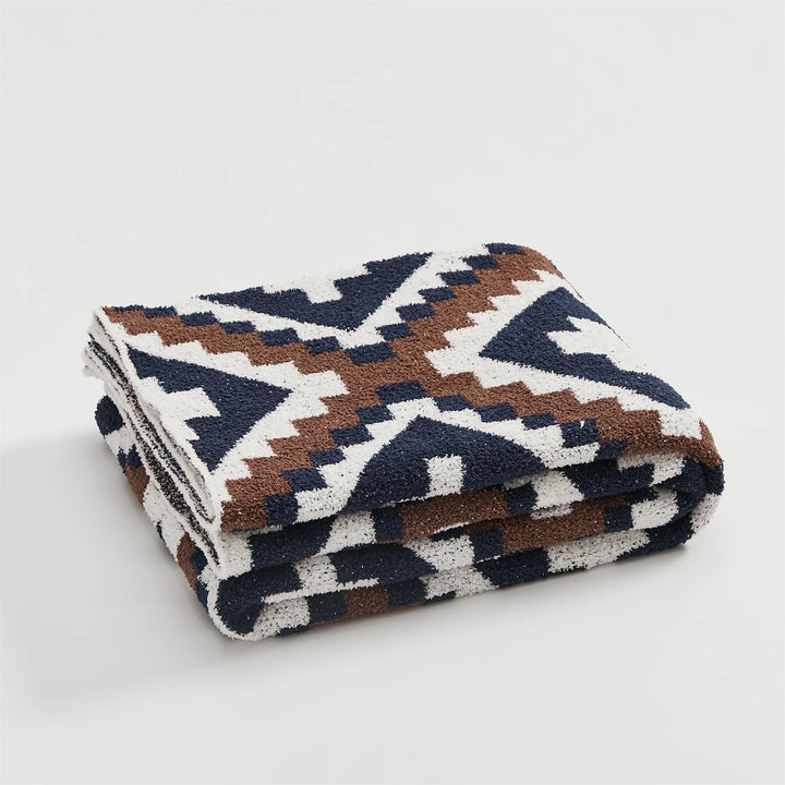 Folded geometric quilt blanket with cream, brown, and navy motifs