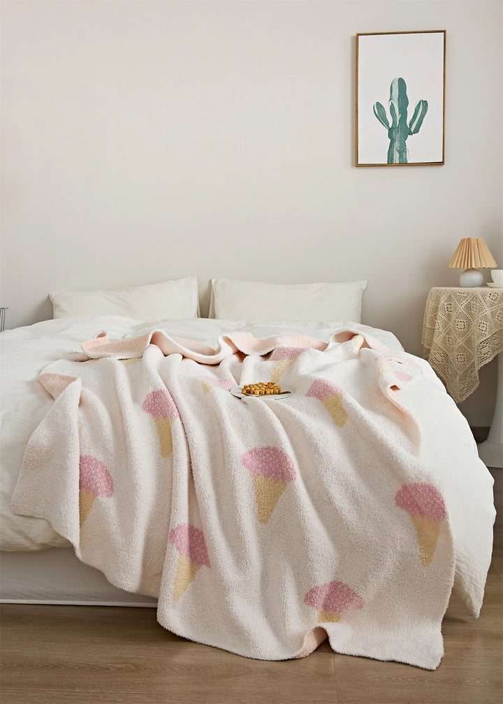 Ice cream pattern blanket spread across a bed, patterned with pink scoops and pale yellow cones