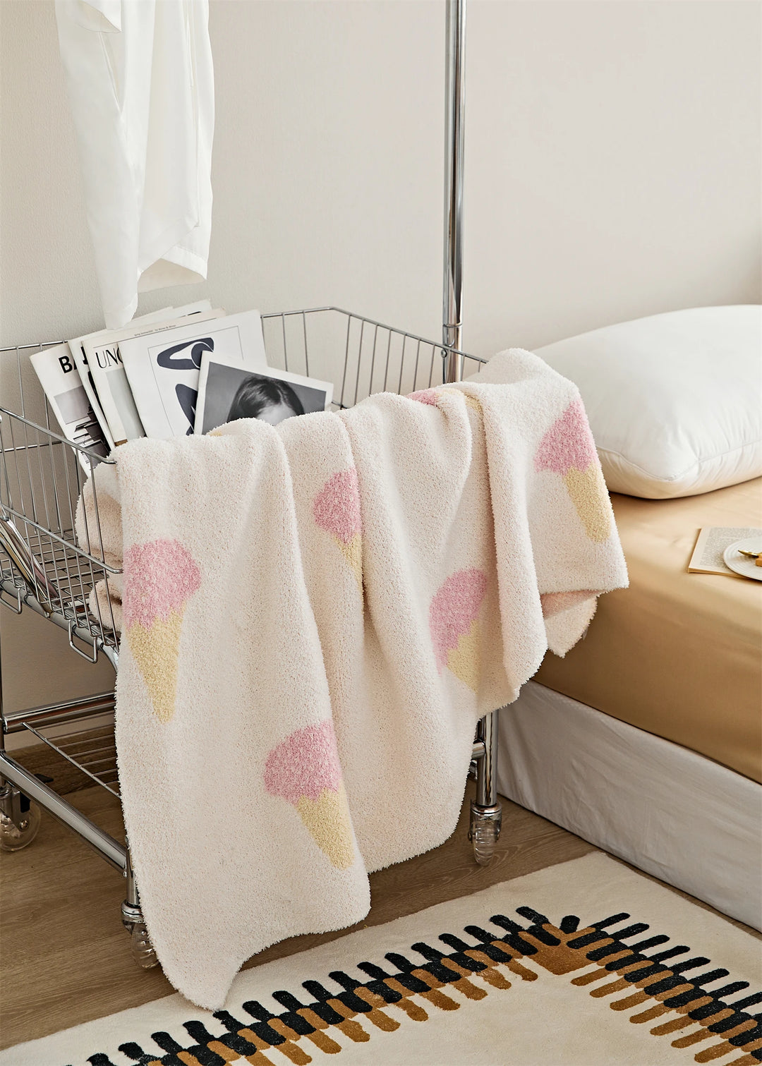 Ice cream pattern blanket draped over a wire cart, displaying repeated pink and yellow cone motifs