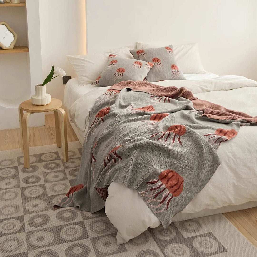 Gray fleece blanket with coral jellyfish pattern and matching pillow covers on a bed
