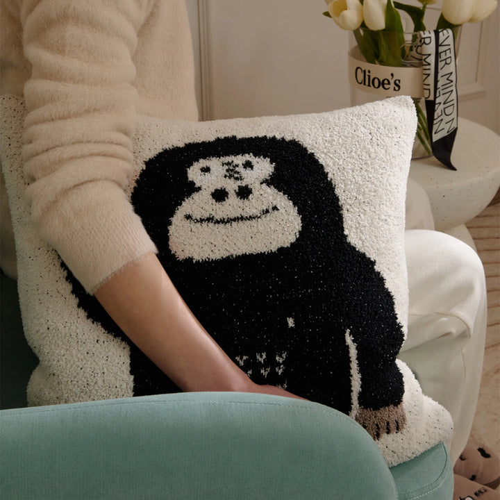 Black gorilla-face Kawaii Gorilla pillow held against a seated person on a teal chair