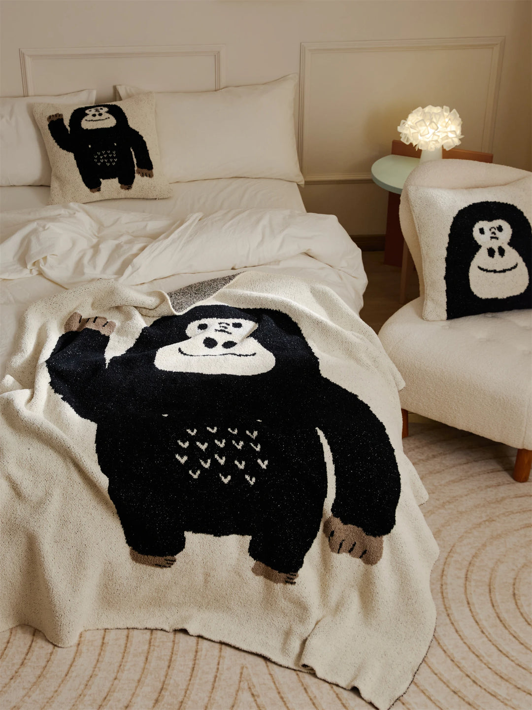 Ivory throw blanket with a black gorilla design spread across a bed