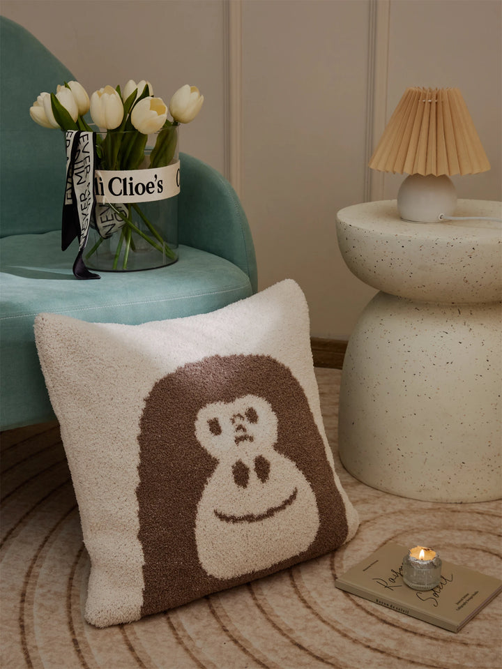 Brown gorilla-face Kawaii Gorilla pillow on a rug beside a teal chair