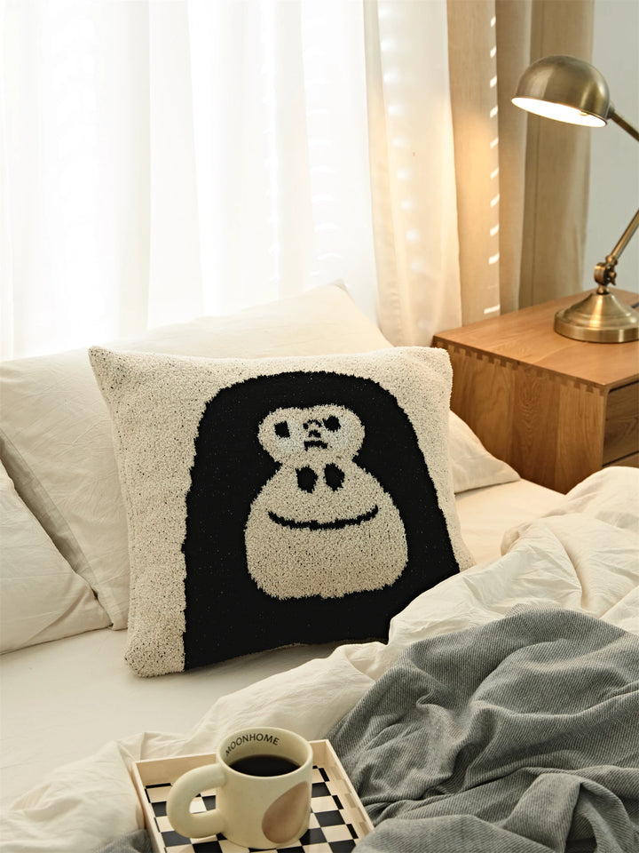 Black gorilla-face Kawaii Gorilla pillow on white bedding beside a wooden nightstand