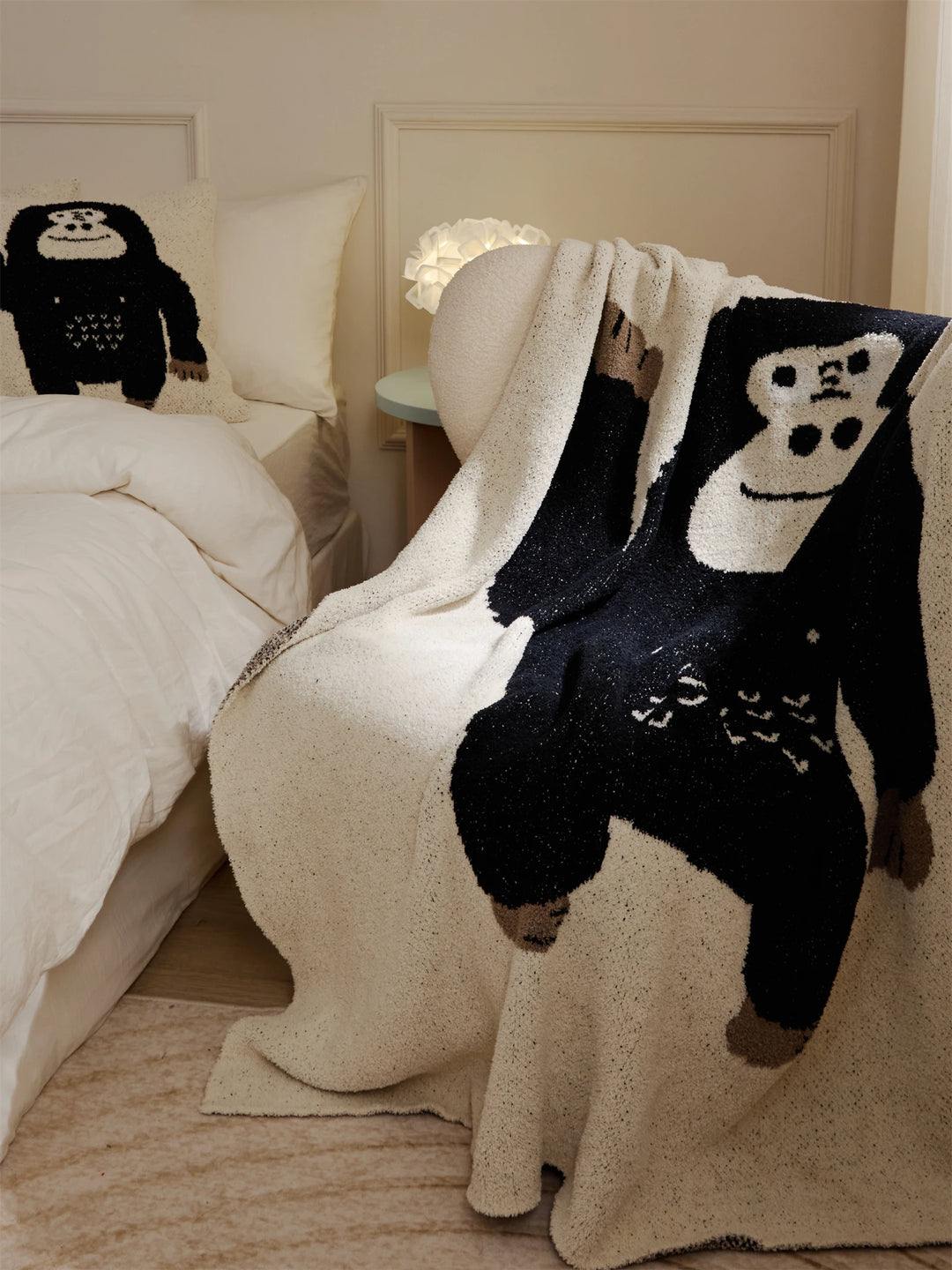 Ivory throw blanket draped over a chair, featuring a black cartoon gorilla