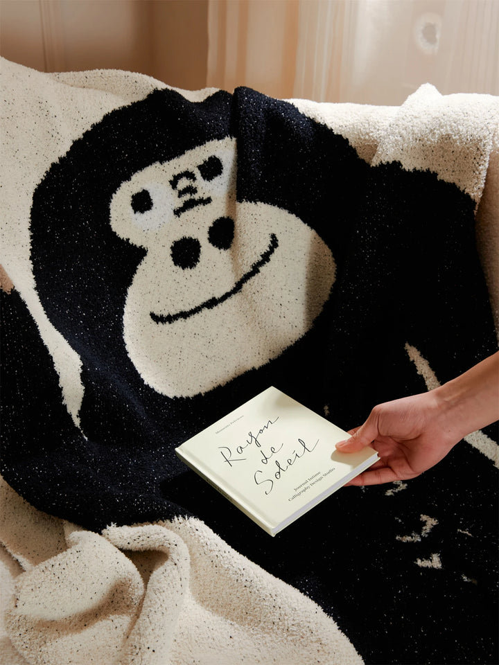 Close-up of a cartoon gorilla design on a plush ivory throw blanket