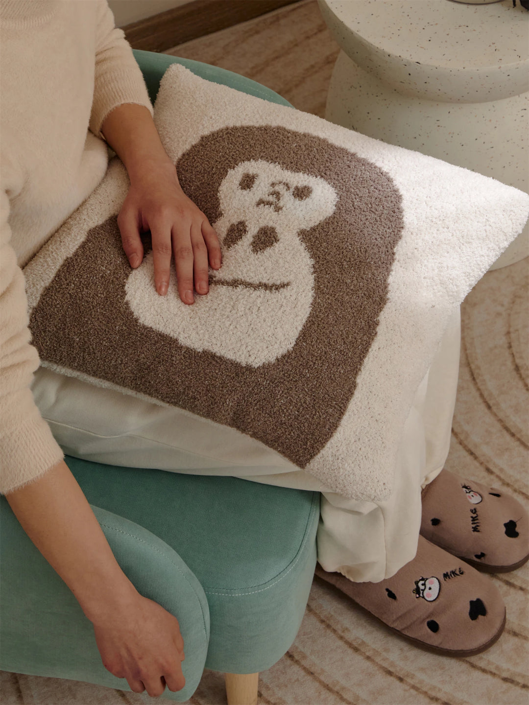 Brown gorilla-face Kawaii Gorilla pillow resting on a seated person’s lap in a teal chair
