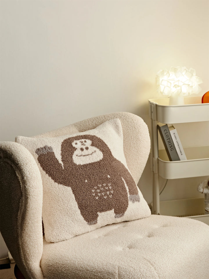 Cream Kawaii Gorilla pillow with a waving brown gorilla on a cream armchair