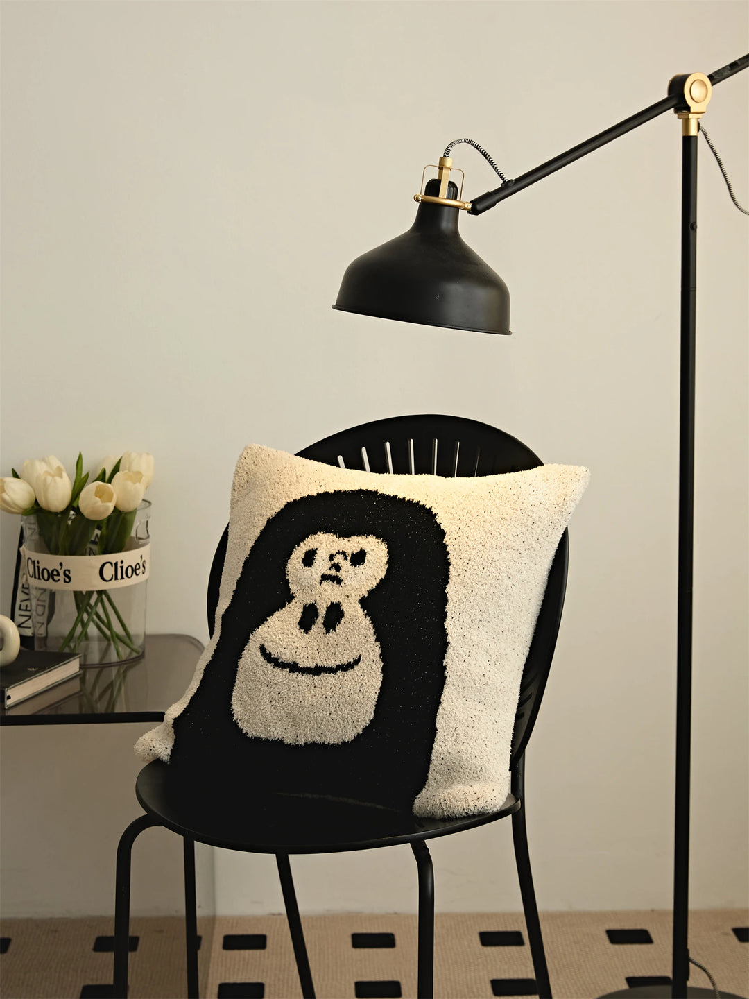 Black gorilla-face Kawaii Gorilla pillow on a black chair under an adjustable floor lamp