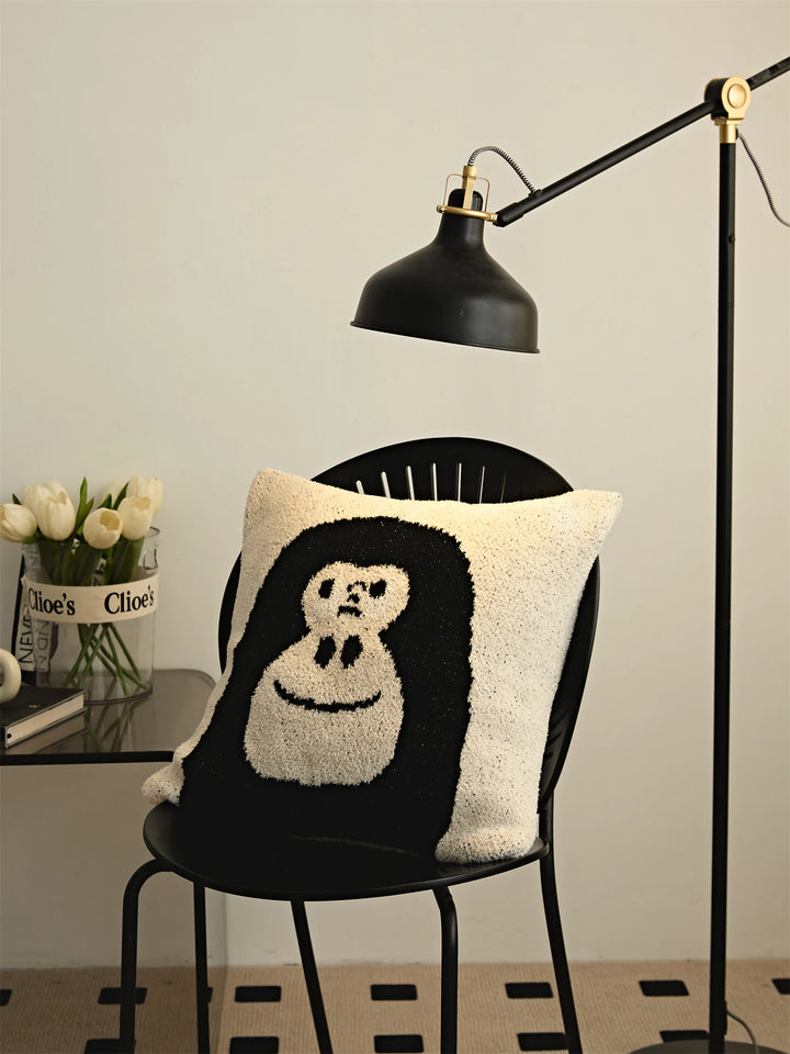 Black gorilla-face Kawaii Gorilla pillow on a black chair under an adjustable floor lamp