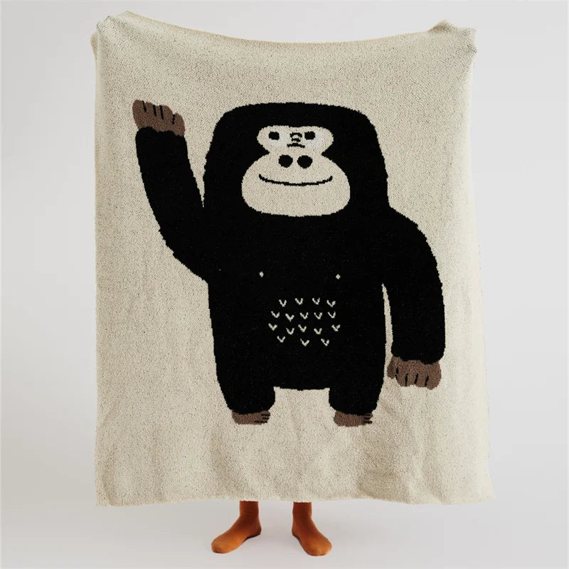 Cream throw blanket with a large black cartoon gorilla and small heart details