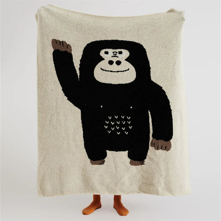 Cream throw blanket with a large black cartoon gorilla and small heart details