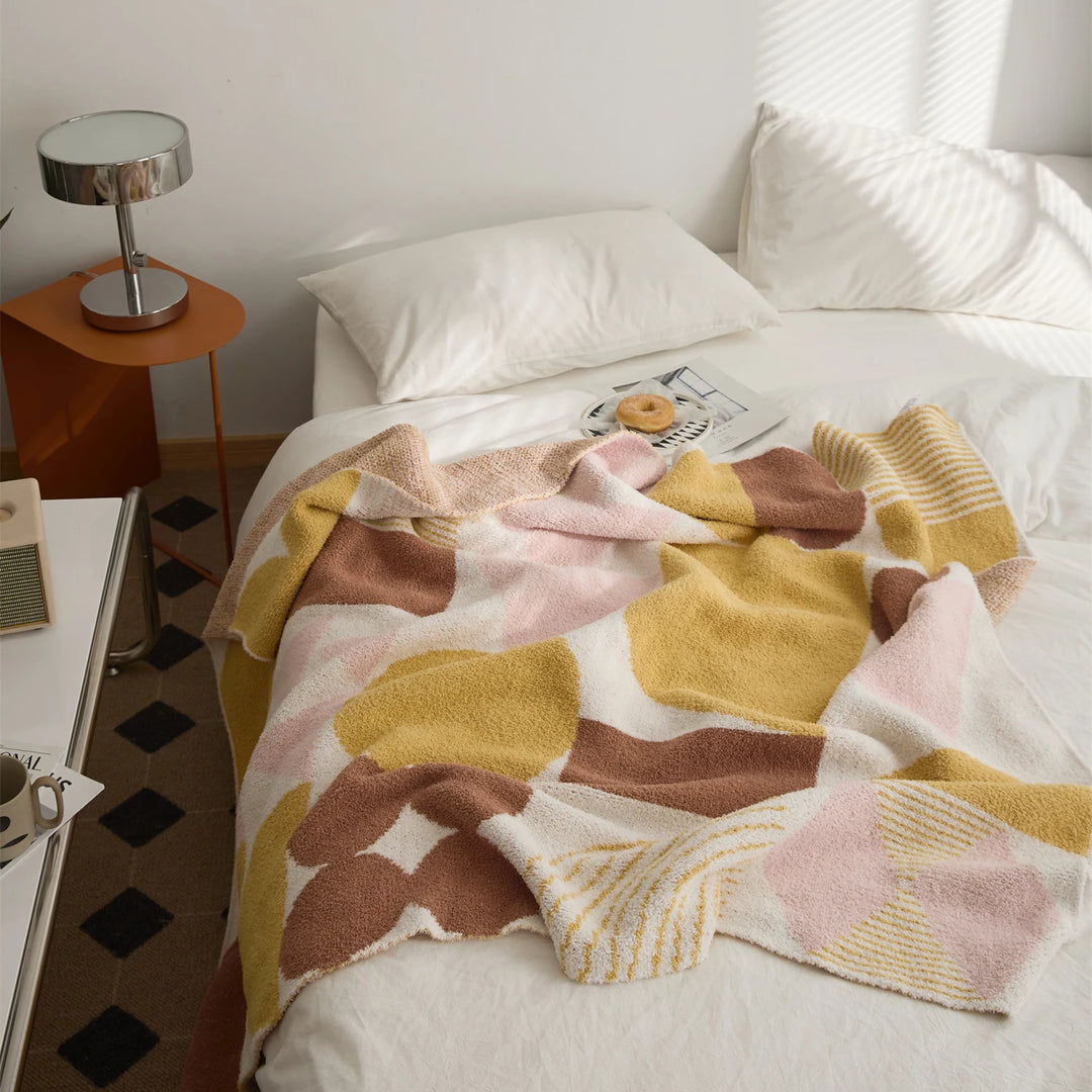 Kawaii Tangram blanket spread over a bed, showing colorful geometric blocks and striped details.
