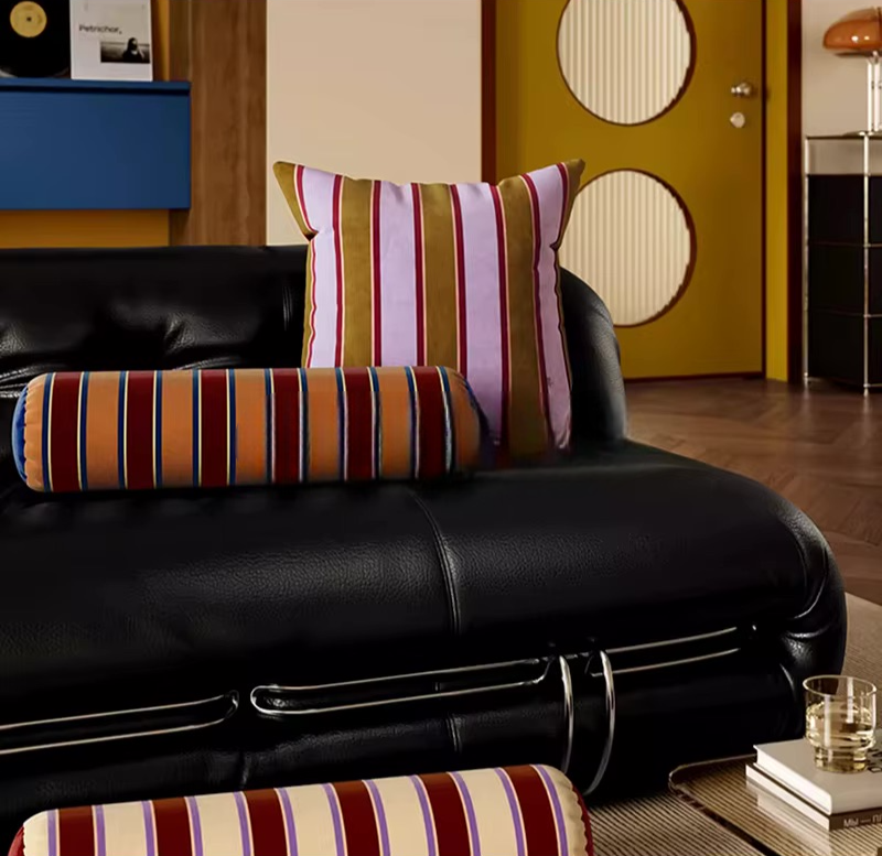 Striped scatter pillows in red, pink, cream, and brown, including square and bolster shapes
