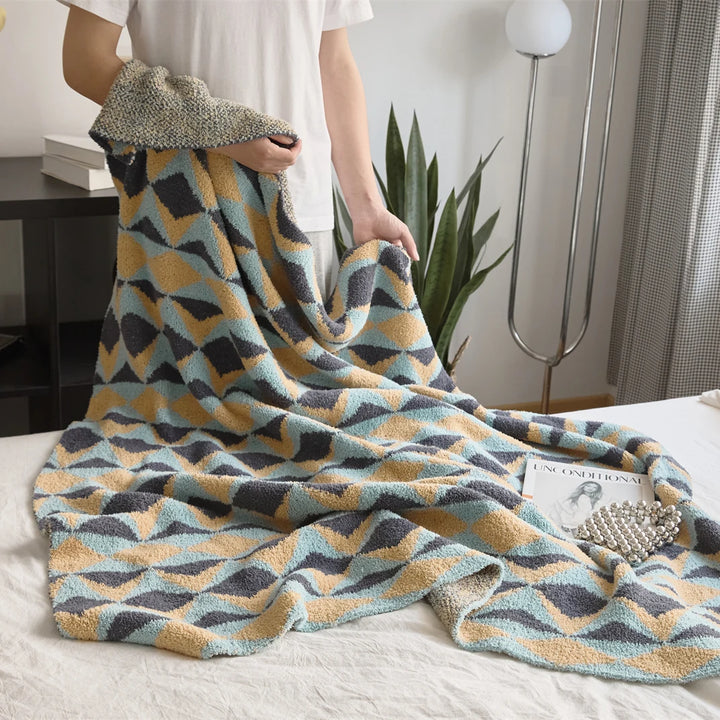Geometric throw blanket with a plush texture and blue, mustard, and charcoal triangles.