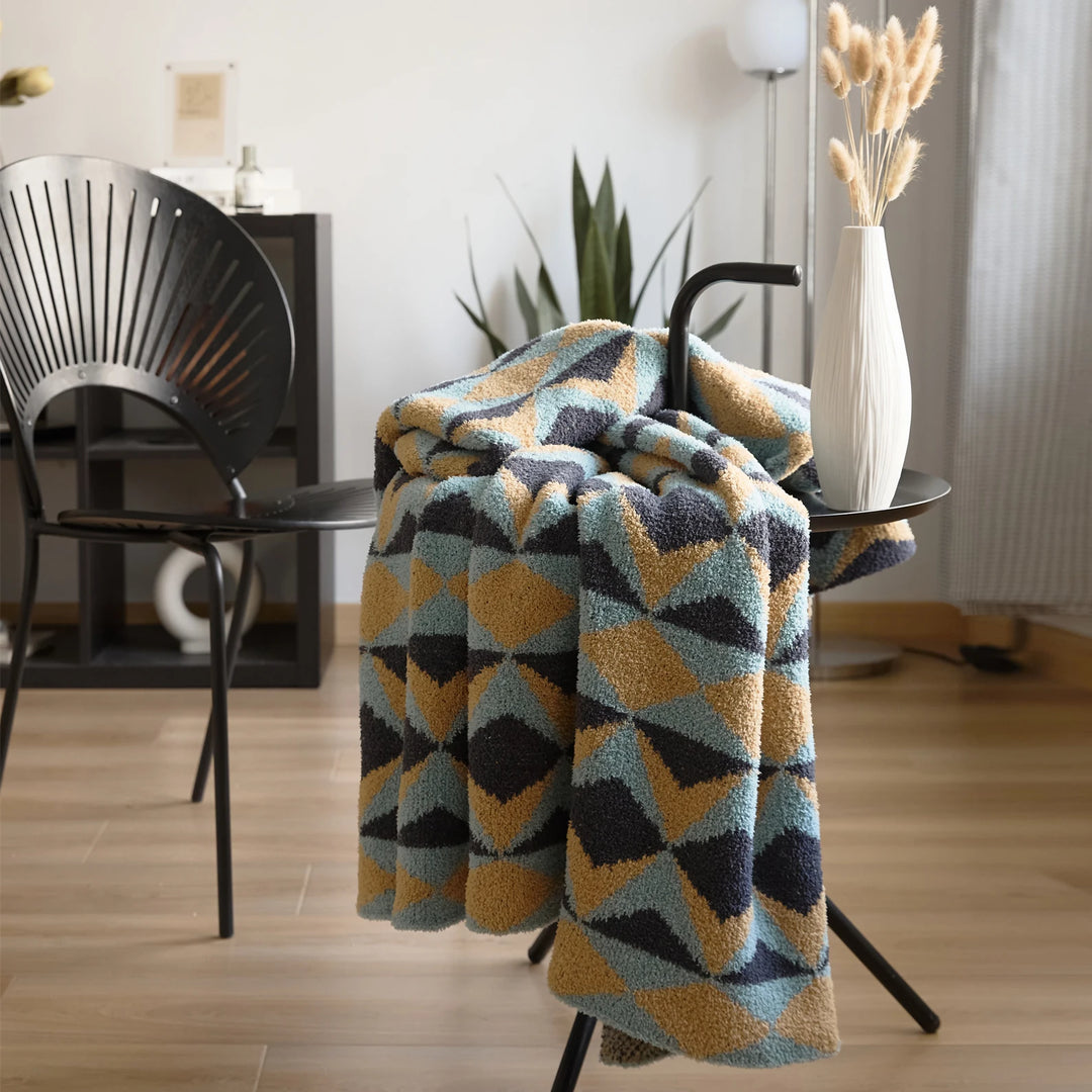 Geometric blanket draped over a chair, with a plush pile and colorful triangle pattern.