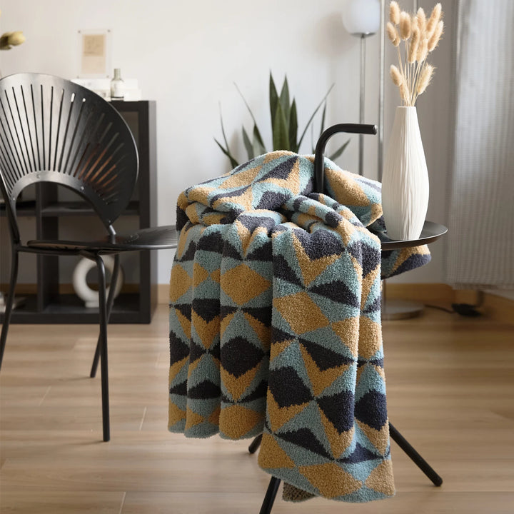 Geometric blanket draped over a chair, with a plush pile and colorful triangle pattern.