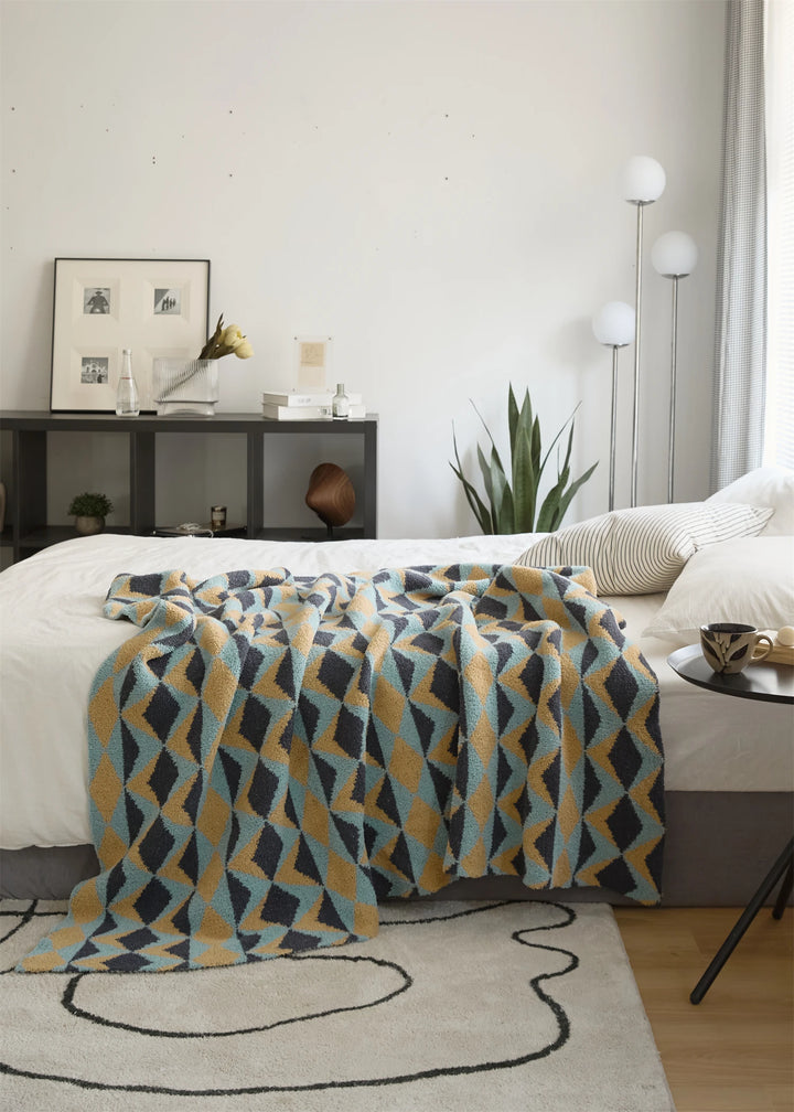 Geometric throw blanket spread over the foot of a bed.
