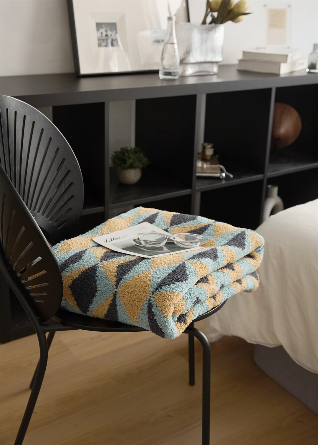 Folded geometric blanket on a chair, showing its thick plush texture.