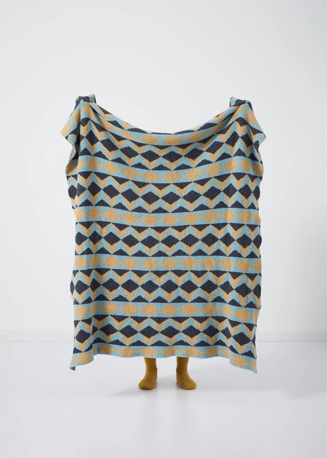 Geometric blanket displayed upright, showing repeating blue, mustard, and charcoal triangles.