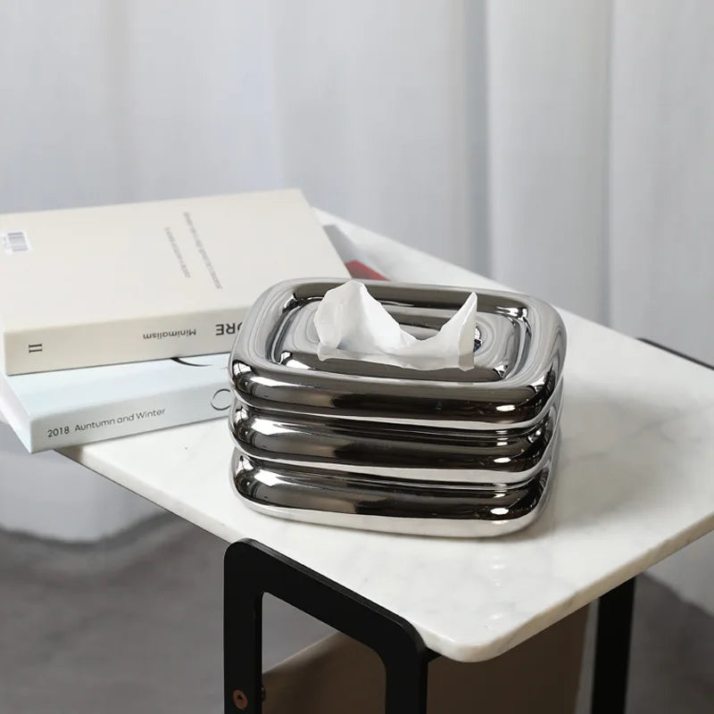 Square silver tissue holder with rounded stacked sides and a tissue pulled through the top.