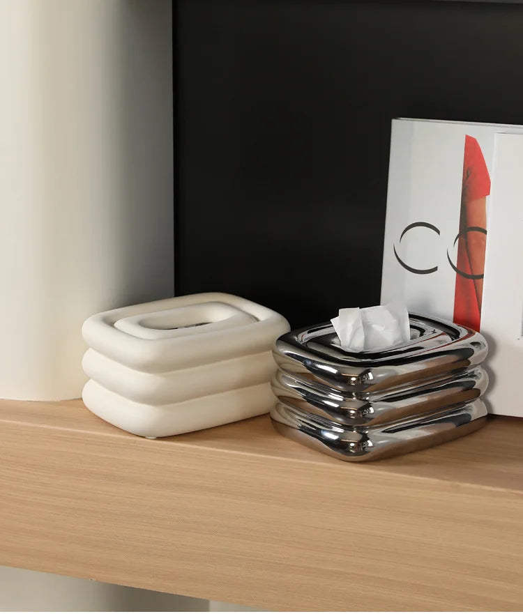 White and silver square tissue holders with rounded stacked sides; a tissue protrudes from the silver one.