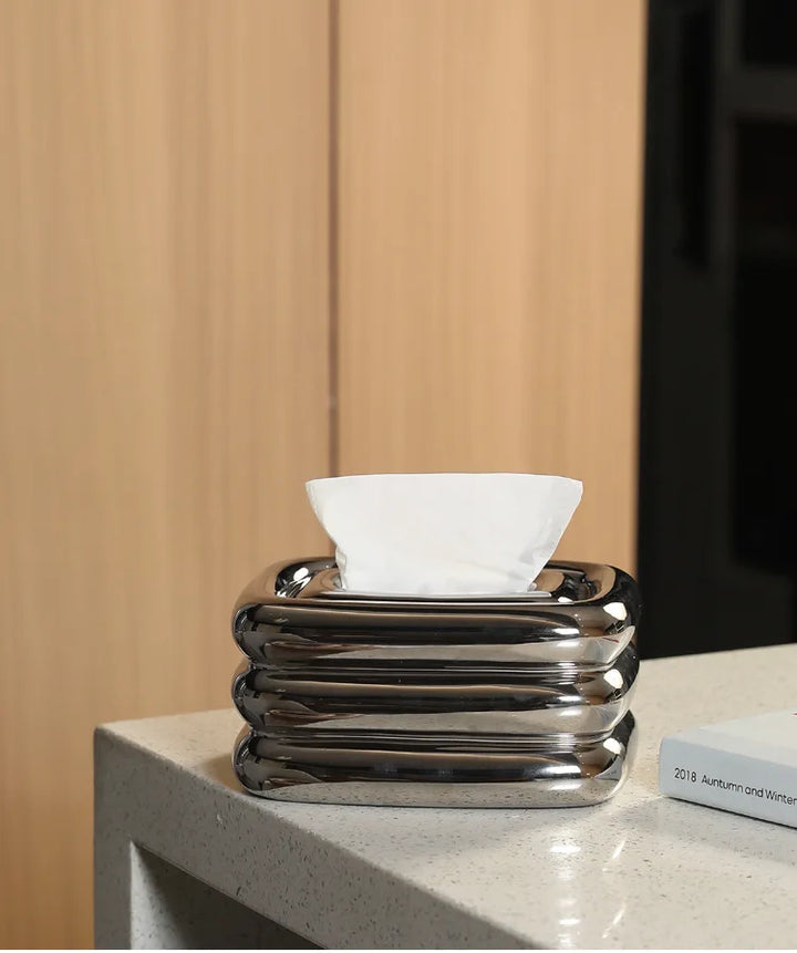 Square silver tissue holder with rounded stacked ridges and a tissue protruding from the top