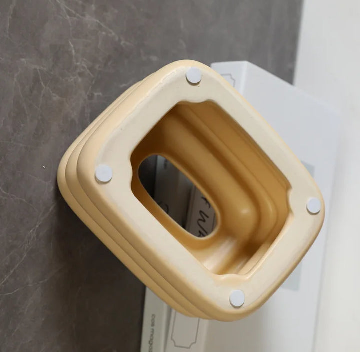 Creamy yellow tissue holder shown from below, with four small feet and a hollow interior