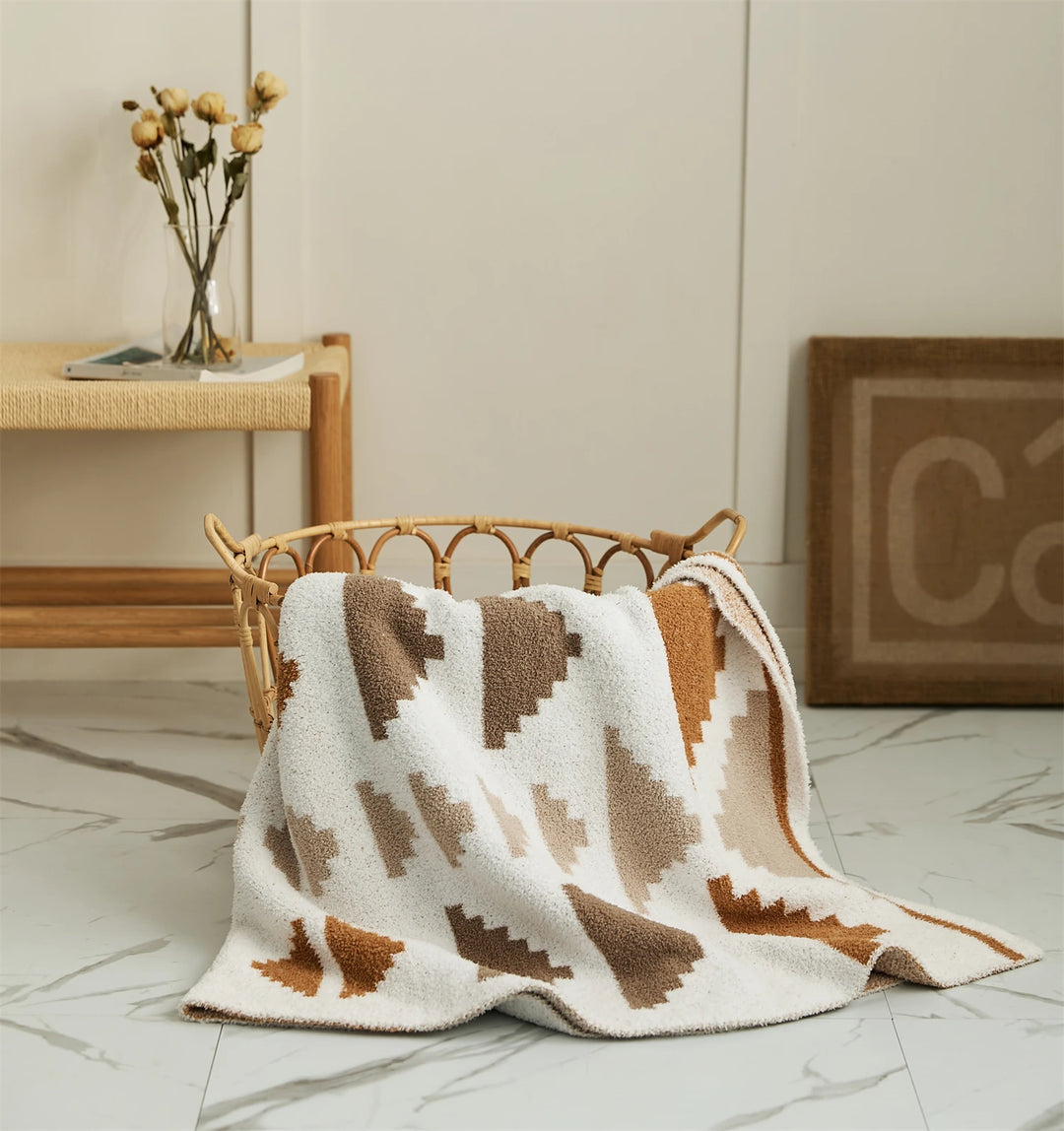Triangle pattern blanket spread over a chair, with cream, taupe, and rust shapes