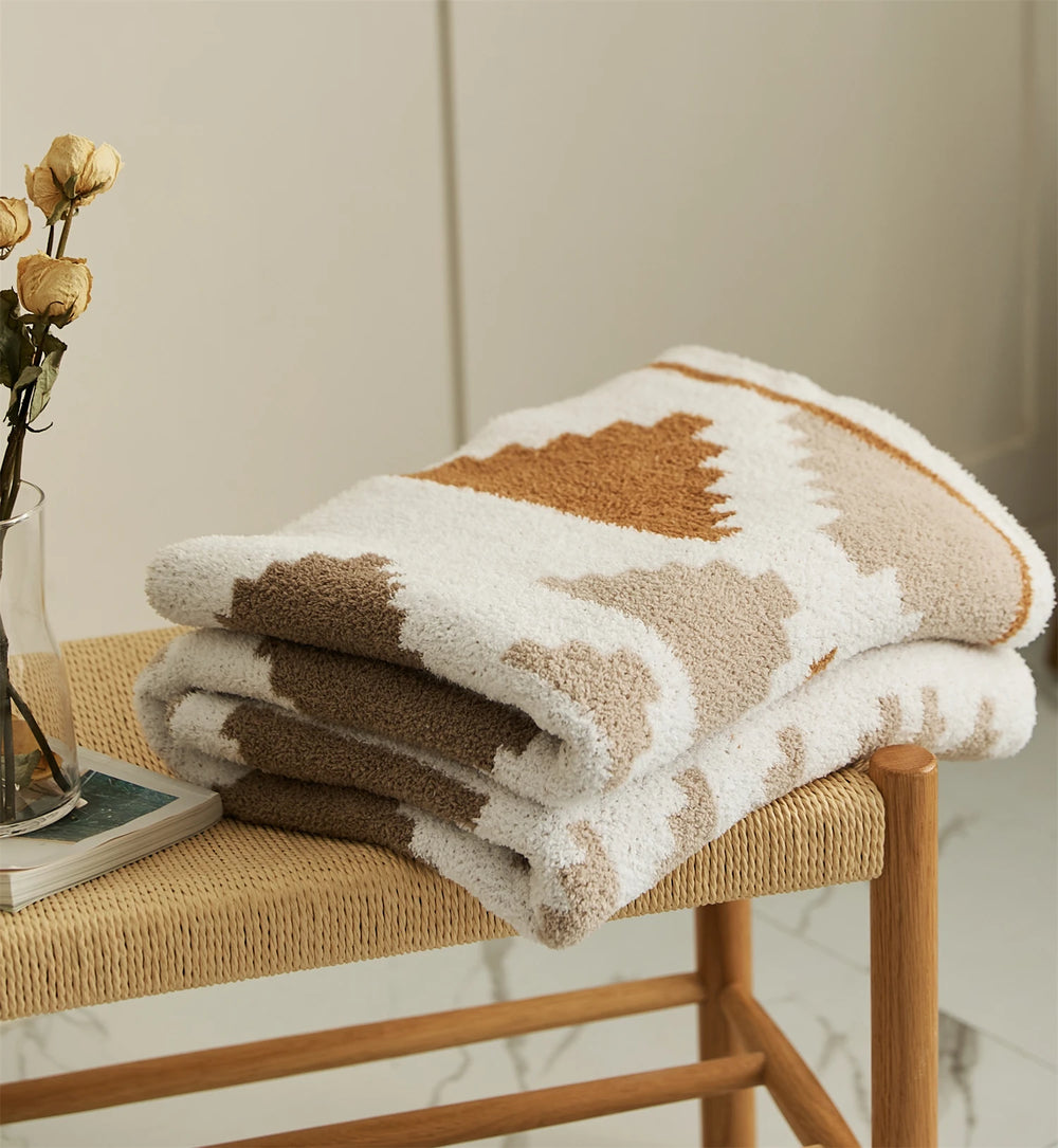 Folded triangle pattern blanket with a plush pile and cream, tan, and rust colors
