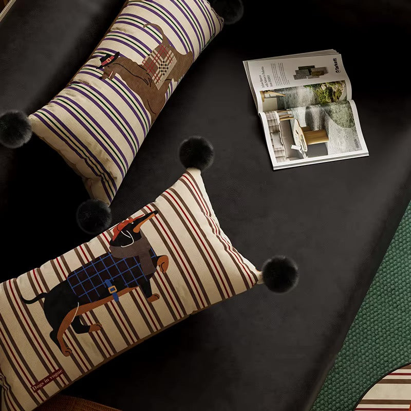 Two striped lumbar pillows with dog illustrations and black pom-pom corners.