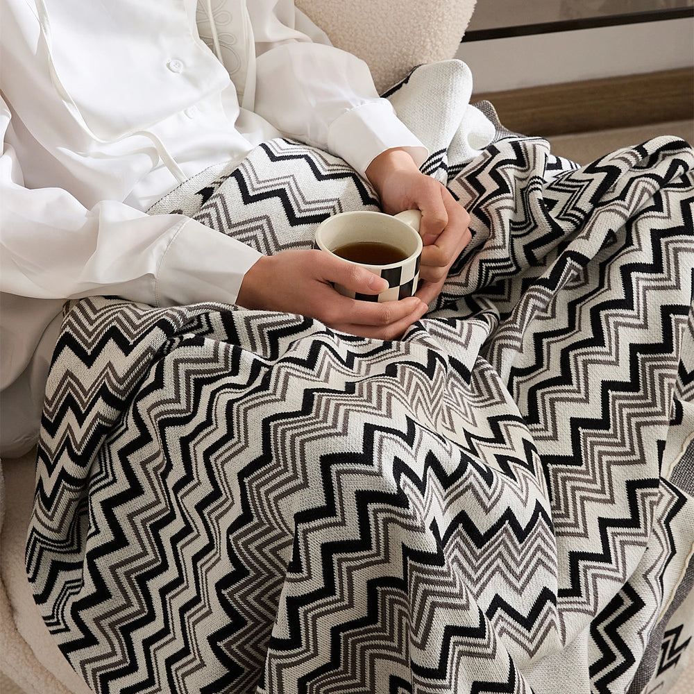 Black and cream wave stripe blanket shown draped across a person's lap