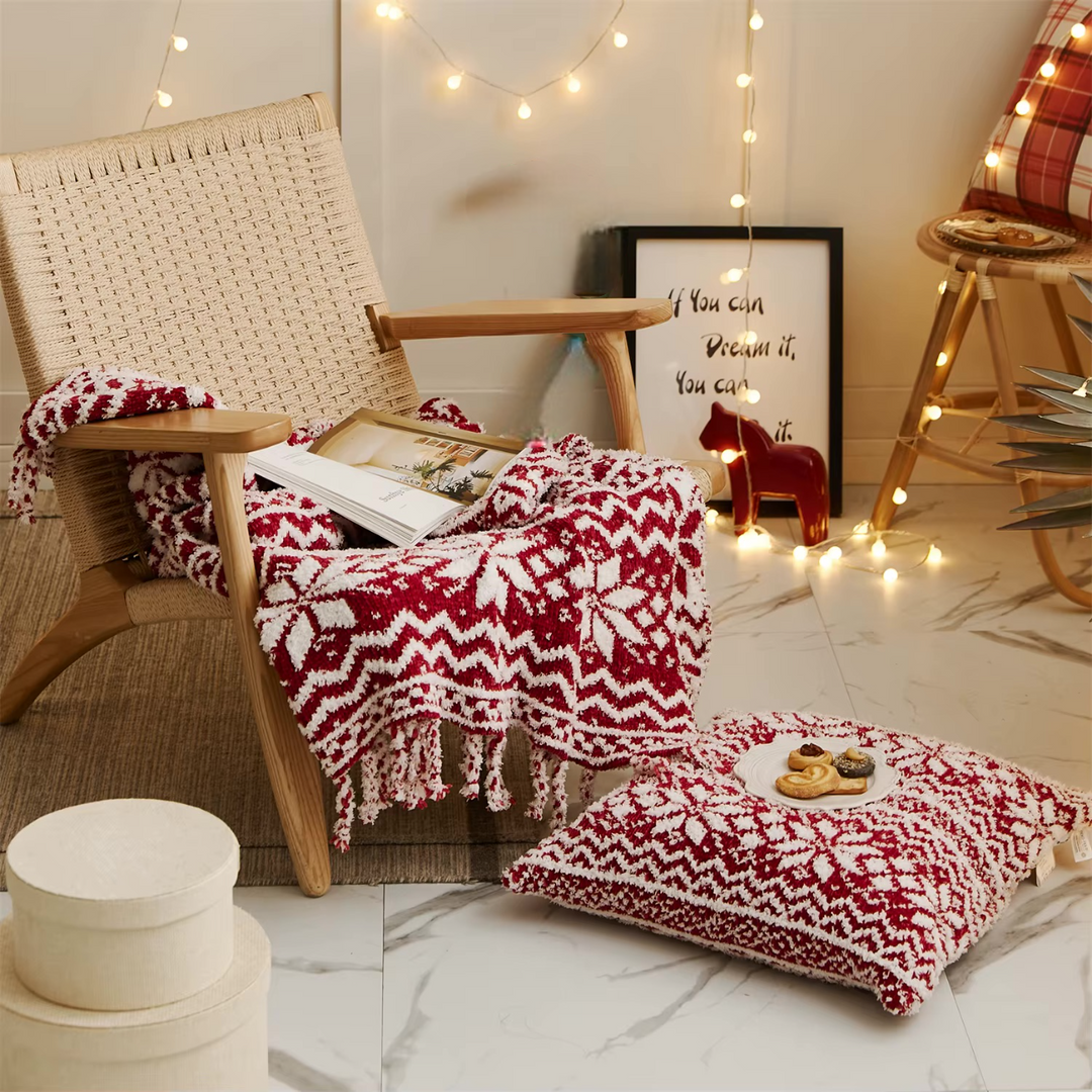 Red-and-white knit throw blanket with fringe, draped over a chair beside a matching cushion