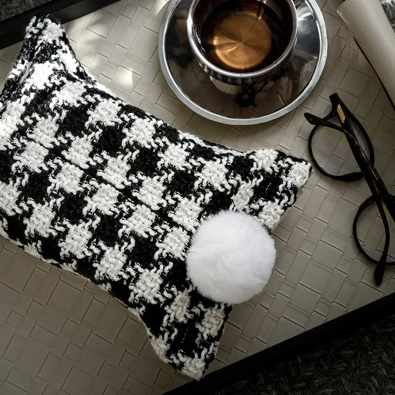 Black and white woven tissue holder with bold checker pattern and white pom-pom