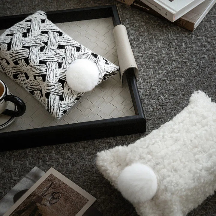 Woven tissue holders with white pom-poms, one with a black and white woven pattern