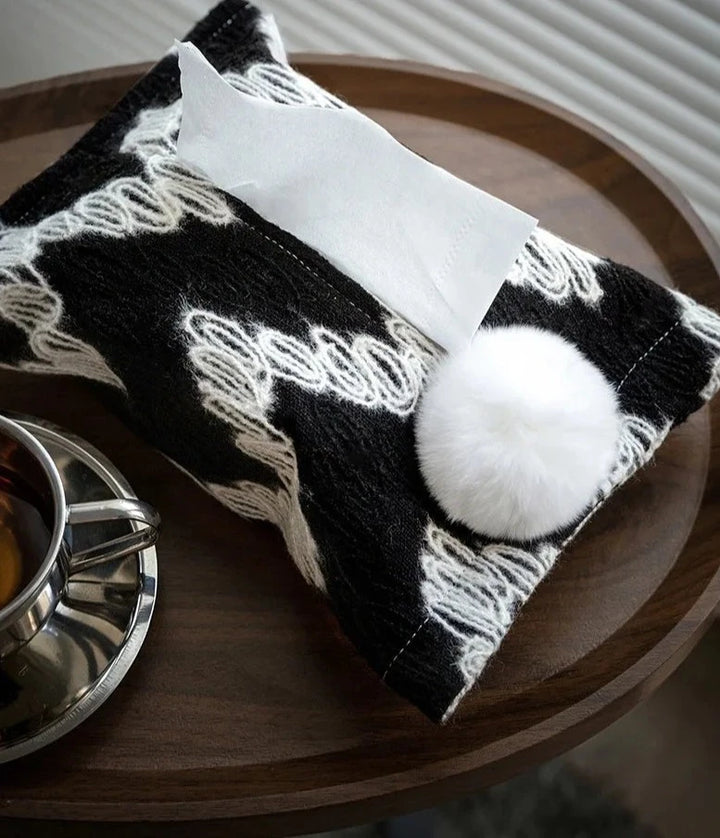 Black woven tissue holder with white wavy pattern and white pom-pom