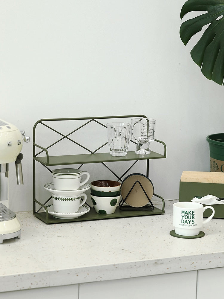 A front view of a green metal shelf with some glass cups and mugs organized on two levels.