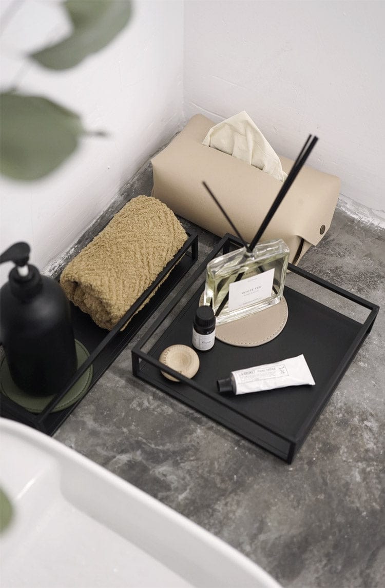 Top view of a metal decoration tray in black with some beauty products.
