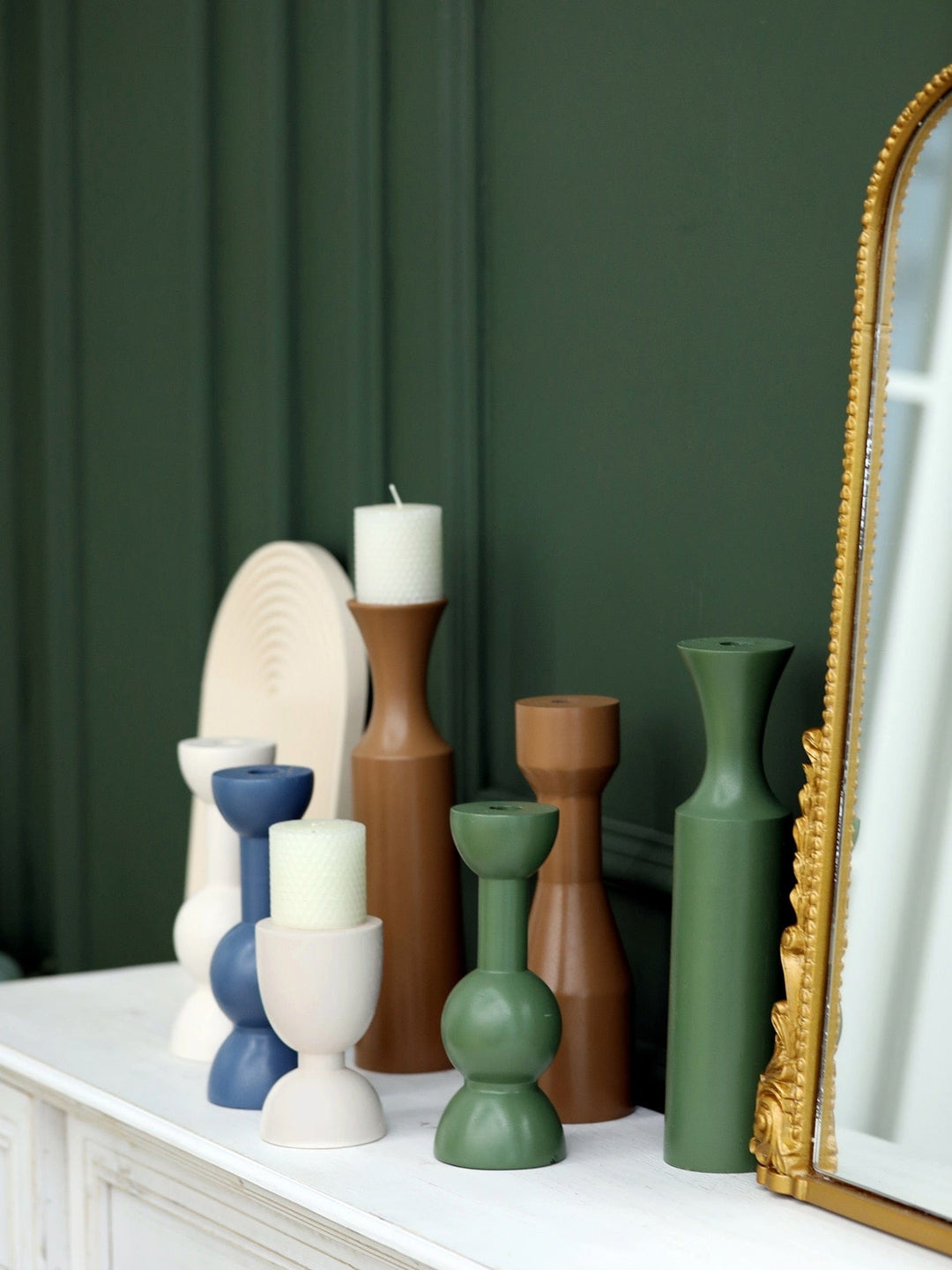 Some colorful hand painted candlestick holders placed on a white finish surface.