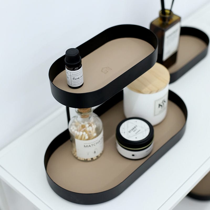 A metal storage tray in black and khaki with varied compartment sizes and some beauty products placed. 