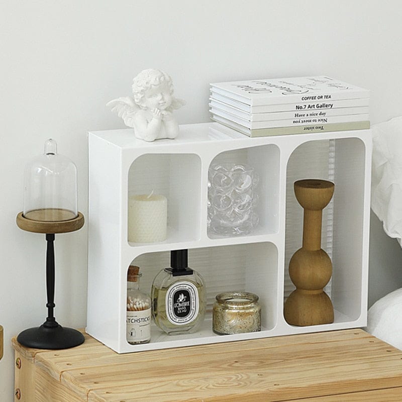 Front view of an acrylic storage holder with white finish having some products organized and a lamp next to it. 